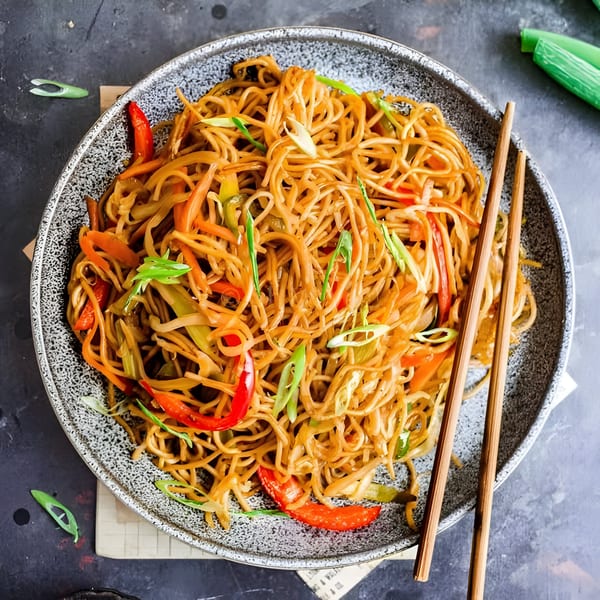 Namaste Taste of India's vegetable noodles with red peppers and green onions, served with chopsticks.