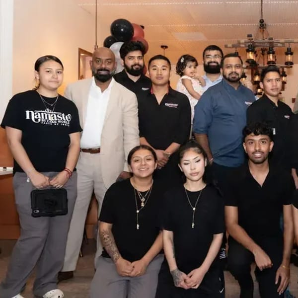 Namaste Taste of India staff, including adults and a child, posing together in the restaurant.