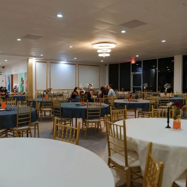 Spacious Namaste Taste of India dining room with round tables, gold chairs, and a few patrons.